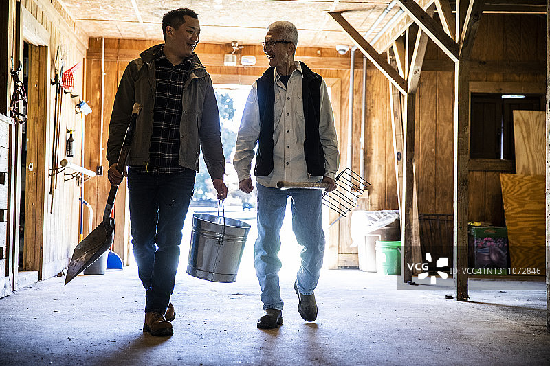 年迈的父亲和成年的儿子走过谷仓图片素材