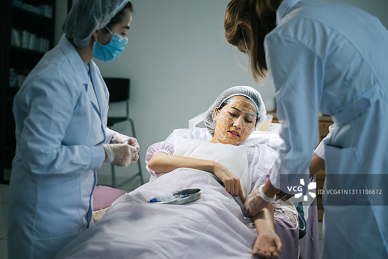 一名亚裔华裔女护士在诊所为一名中国女性患者的手臂静脉采血图片素材