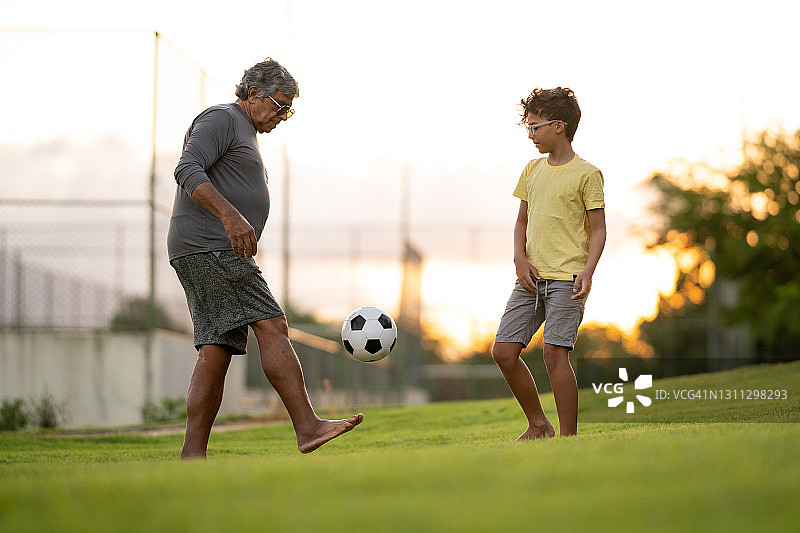 小男孩和他爷爷在公园里踢足球图片素材