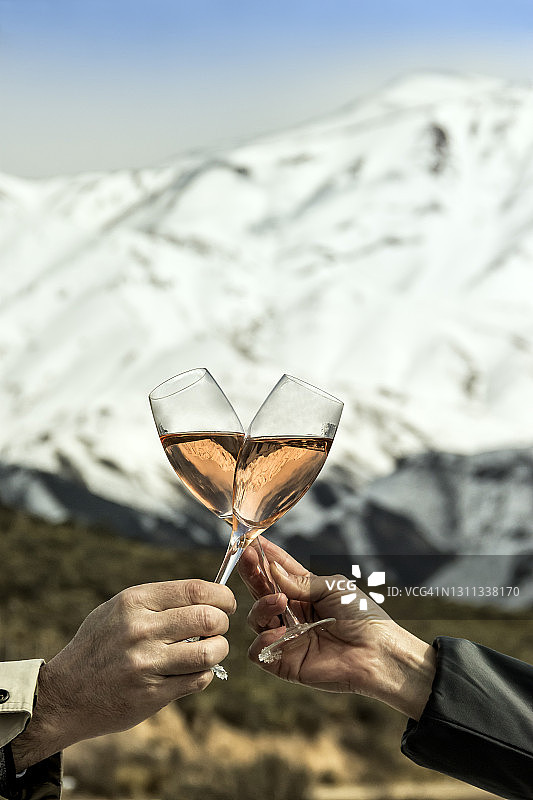 情侣们在雪山中举杯庆祝。图片素材