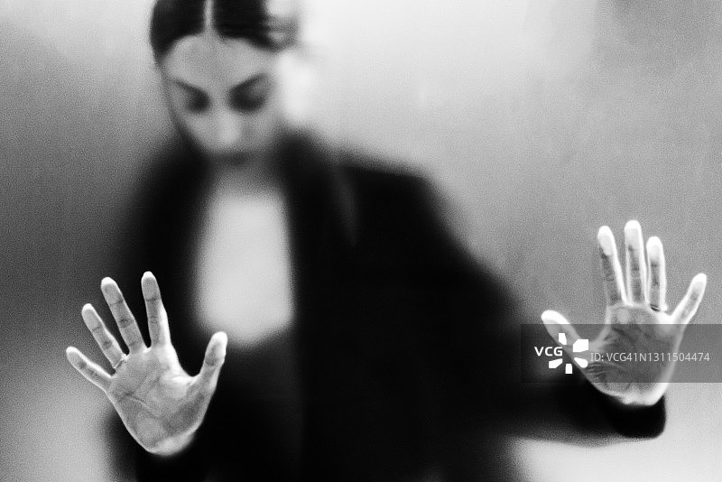 女性在磨砂玻璃后的恐惧手势图片素材