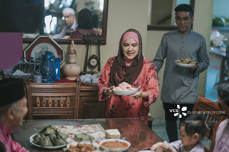 斋月Hari Raya马来人的祖母，儿子和儿媳在餐厅为家人提供食物图片素材