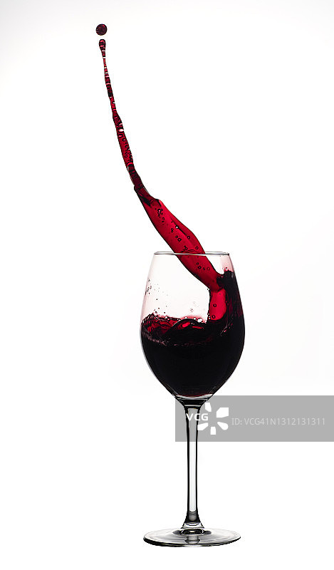 在白色背景前，红酒飞溅在杯子里图片素材
