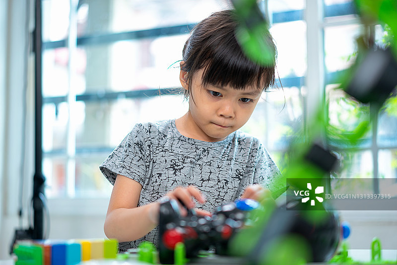 一个女孩在自动化课堂上聚精会神地组装玩具机器人。图片素材