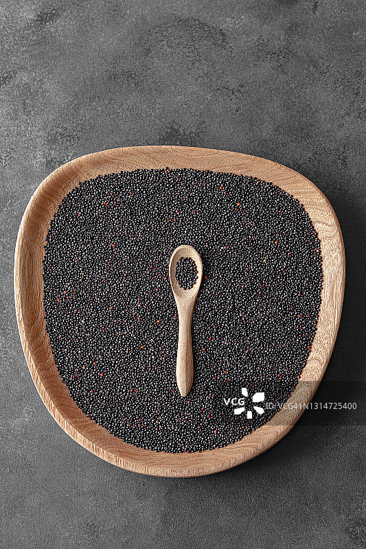 微距摄影生的有机藜麦种子(藜麦藜)在木勺上的黑色背景，俯视图图片素材