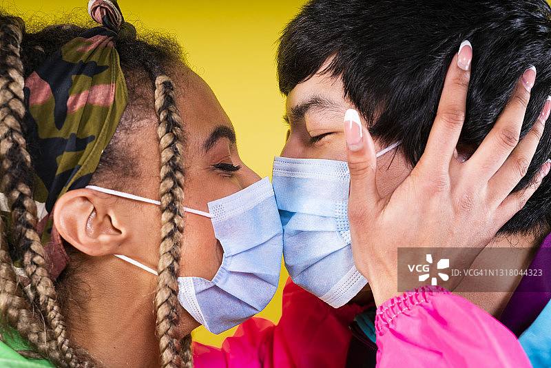 年轻夫妇戴着保护面罩亲吻对方图片素材