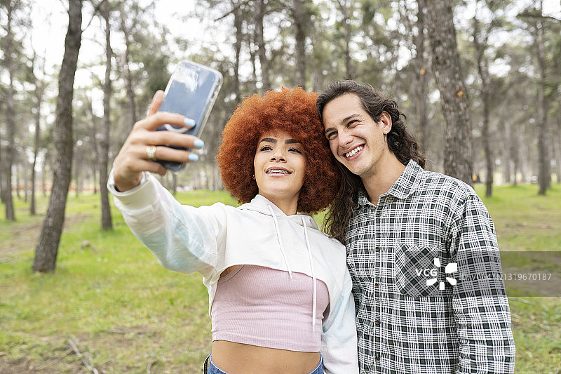 年轻女子和男子在森林里用手机自拍图片素材