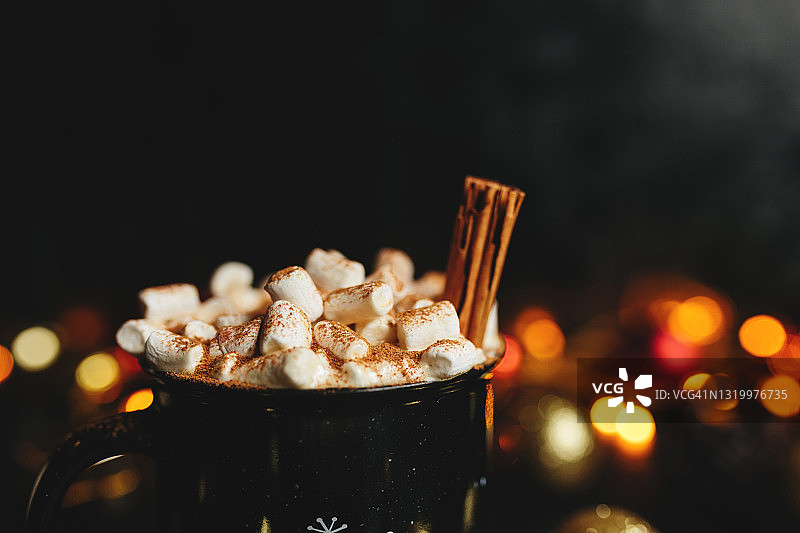 圣诞热巧克力，棉花糖和肉桂在黑色的桌子上，圣诞灯花环。2021年新年概念图片素材