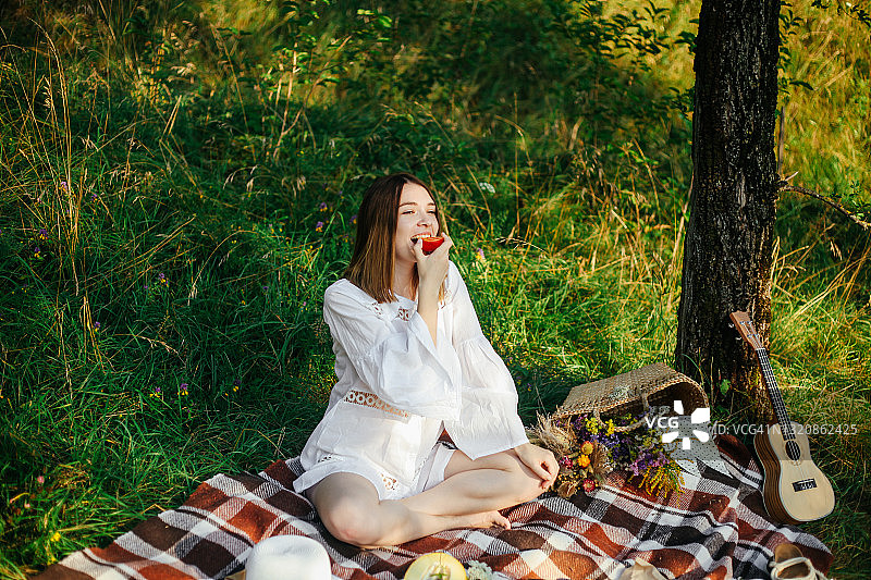 夏日自然写真，年轻轻松的户外女子。野餐和休闲活动的概念。绿地公共公园背景。图片素材
