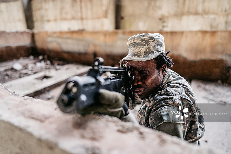 一名年轻的陆军士兵注视着瞄准器并瞄准目标图片素材