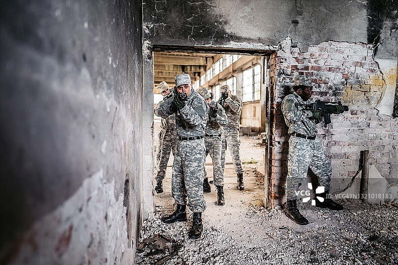 军事突击小队在废弃建筑的走廊里盯梢图片素材