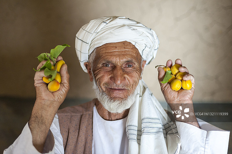 阿富汗潘杰希尔山谷，一名男子手里拿着一把刚从他的农场里摘下来的杏图片素材