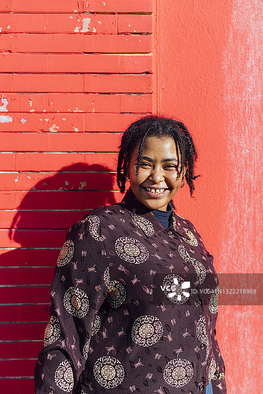 女人微笑着站在红墙前图片素材