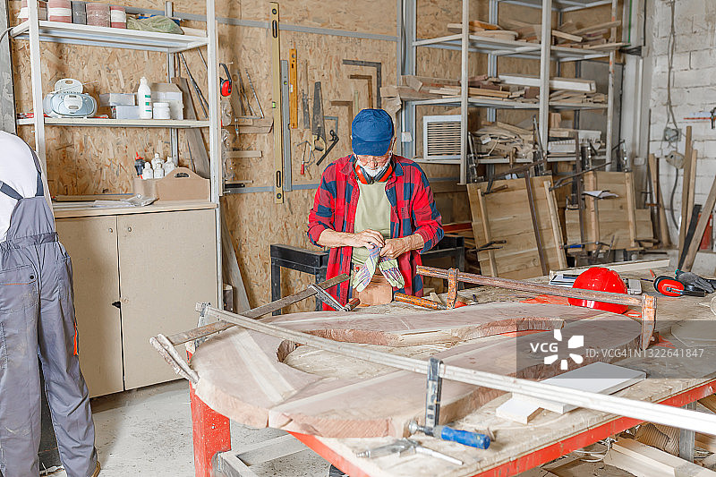 在木工工厂里，自信的木匠正在塑造一块木板。图片素材