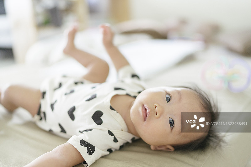 俯视图面部表情亚洲女婴(0-3个月)在舒适的床上打扮得非常可爱和清晰的背景图片素材
