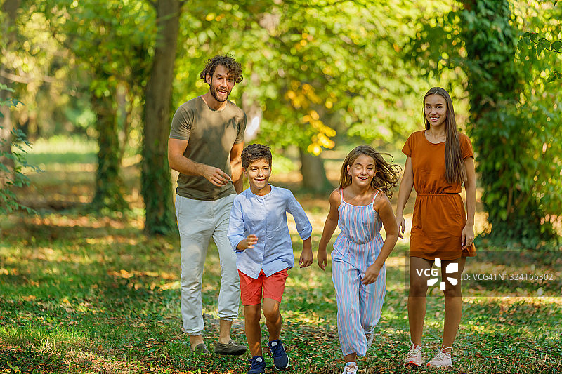 幸福家庭和他可爱的孩子们在公园里散步。图片素材