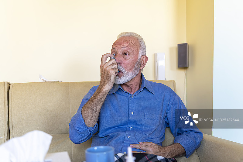 有呼吸问题的哮喘男子正在使用吸入器解决呼吸问题。图片素材