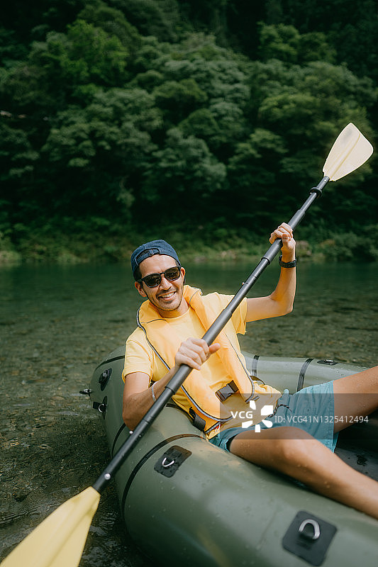 日本，一名男子微笑着划着皮划艇穿过河流图片素材