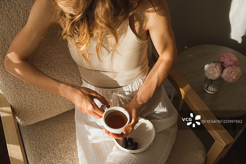 在阳光明媚的公寓里喝早茶的女人。图片素材