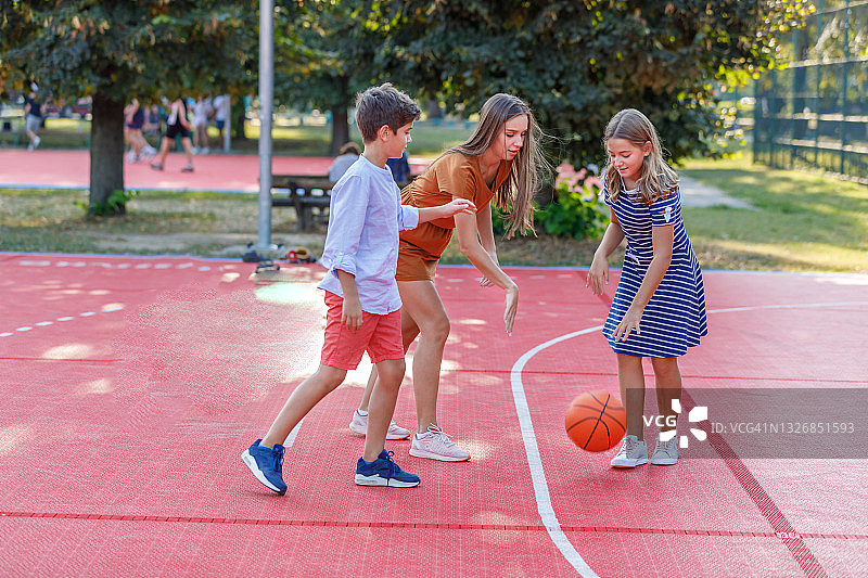 快乐家庭在公园里玩篮球。图片素材