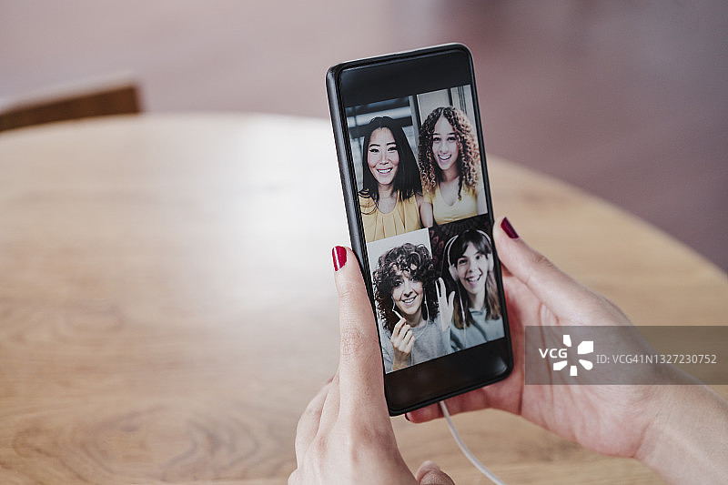 一名年轻女子在咖啡店里与女性朋友通过智能手机视频通话图片素材