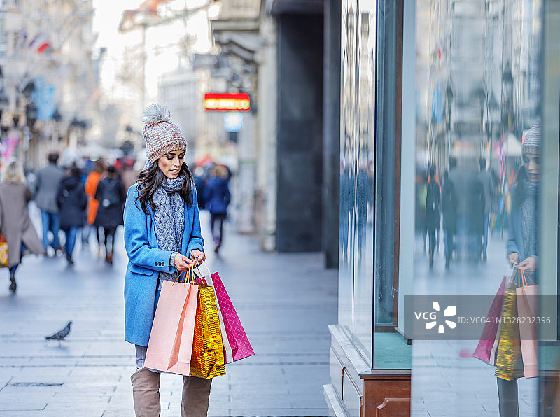快乐女人是在城市的街道上度过一个购物日。图片素材