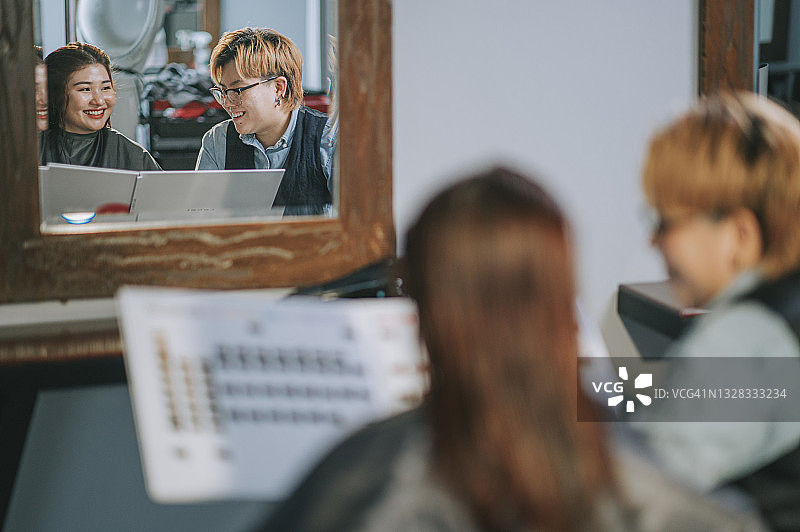 发廊亚洲华人女性发型师展示发色图给顾客讨论并推荐图片素材