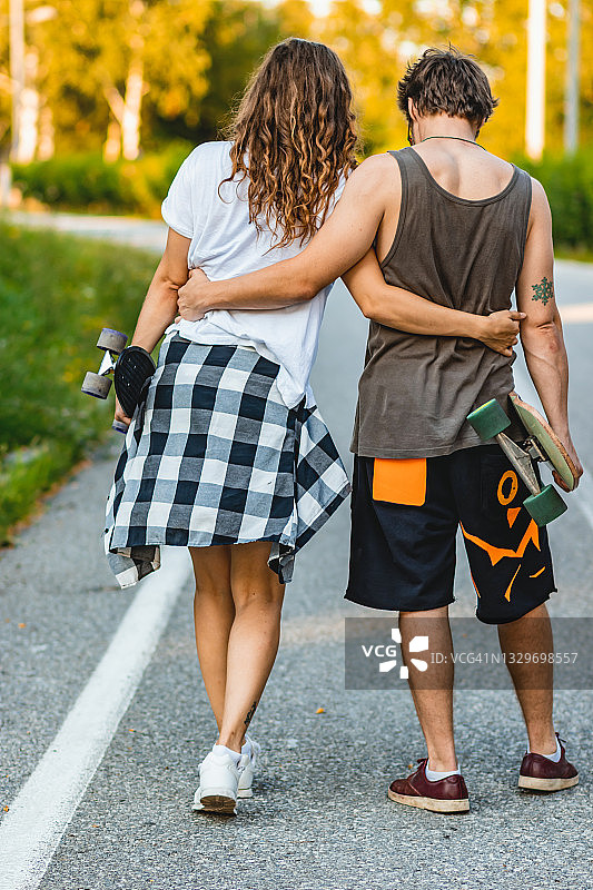 一对年轻夫妇在路上玩滑板图片素材