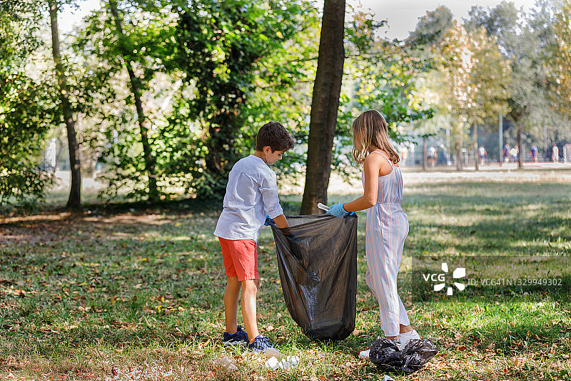 快乐的小朋友们正在用塑料袋收集垃圾。图片素材