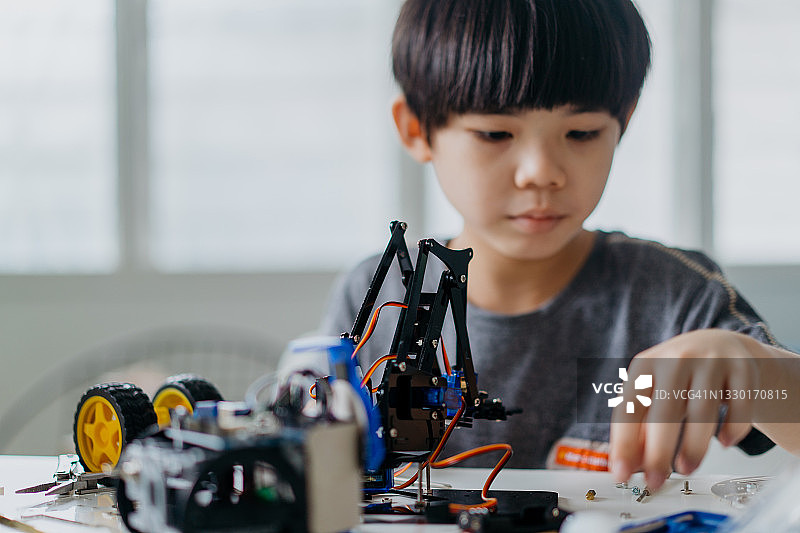 年轻的亚洲男孩在家里制作机器人玩具图片素材