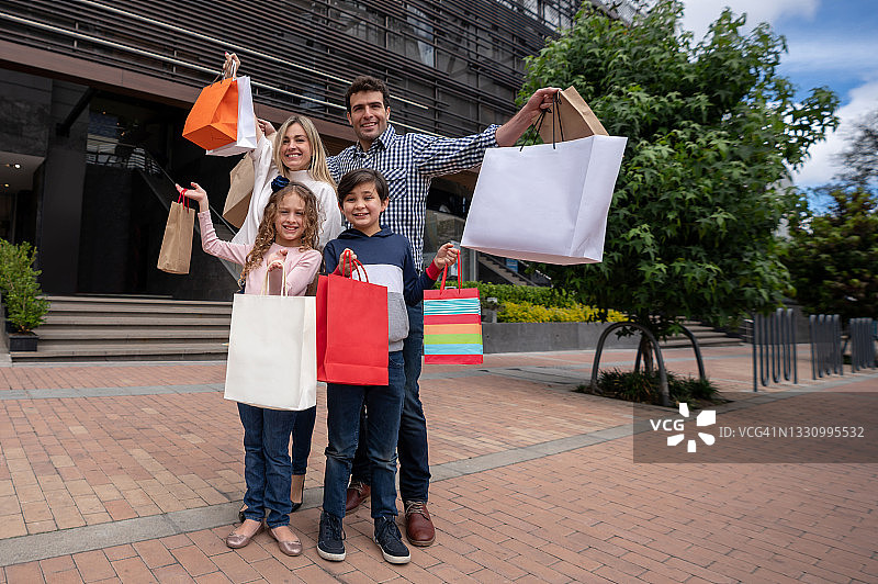 一家人在商场购物，拿着袋子，看起来很开心图片素材