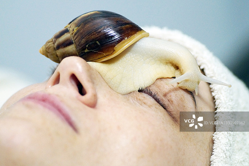 一位40岁的妇女用蜗牛让她的脸焕发青春图片素材