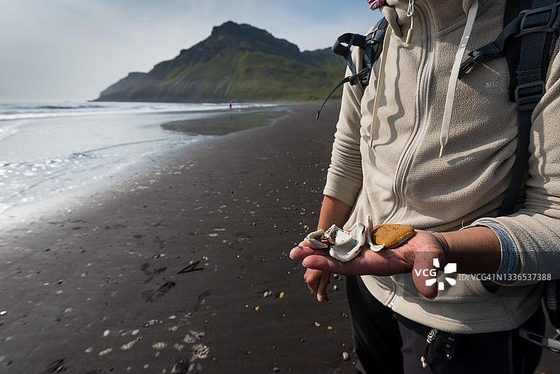 手拿贝壳的女人，海滩，布雷达维克，东峡湾，维克纳斯洛迪尔，冰岛图片素材