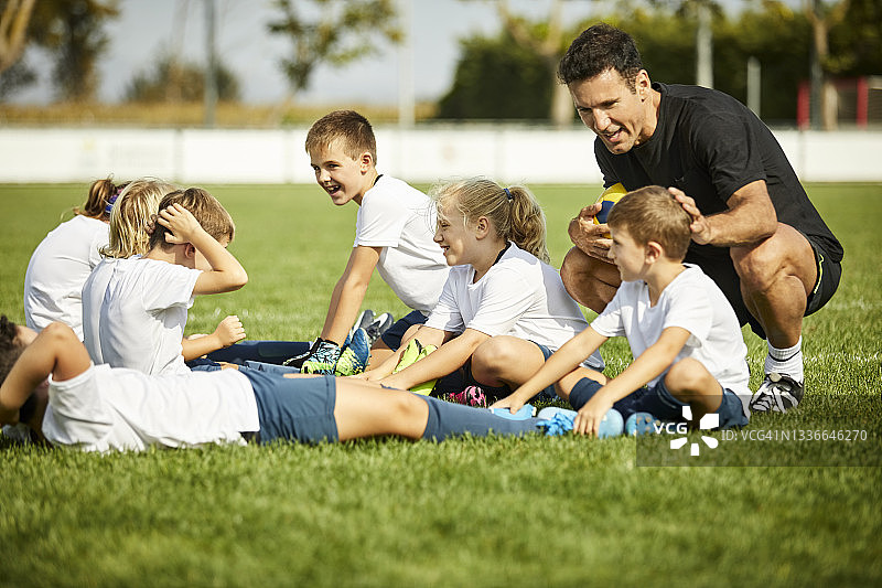 男教练在草地上和孩子们说话图片素材