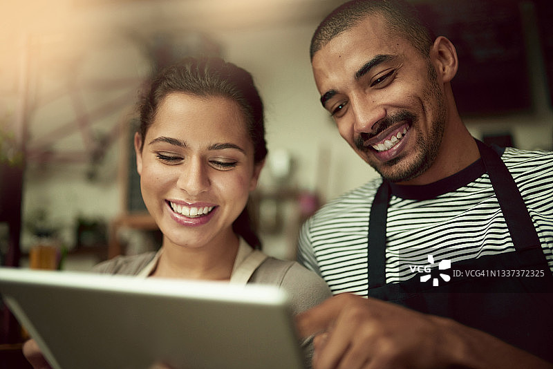 一名年轻男子和一名女子在咖啡馆工作时一起使用电子平板电脑图片素材
