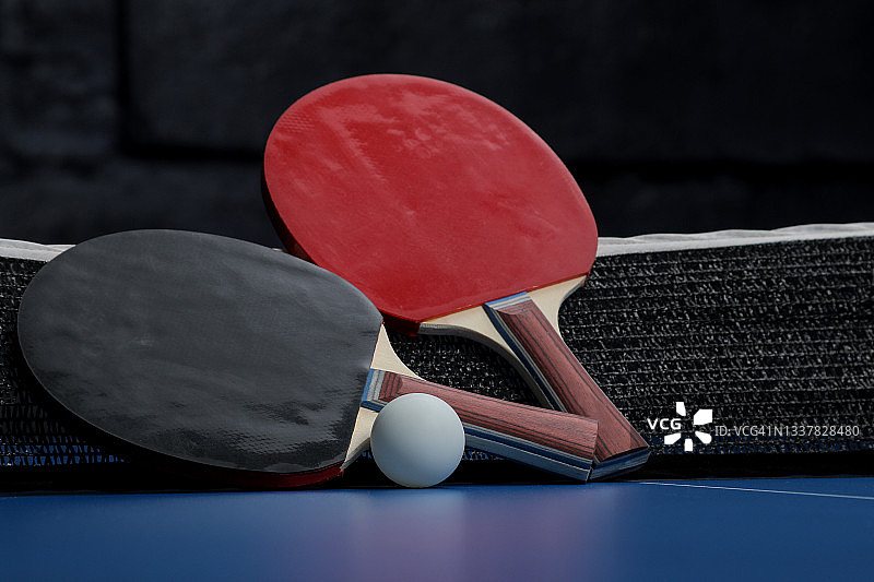 乒乓球。乒乓球拍子和球的配件，放在蓝色的乒乓球桌上。运动。体育游戏。图片素材