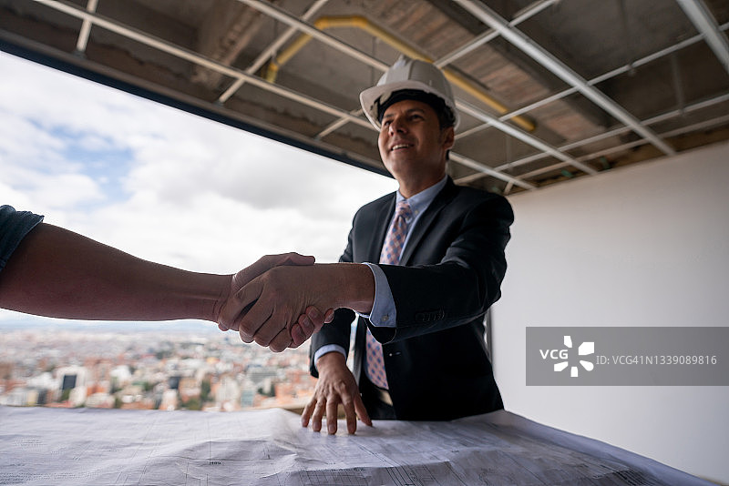 建筑师在建筑工地与客户握手问候图片素材