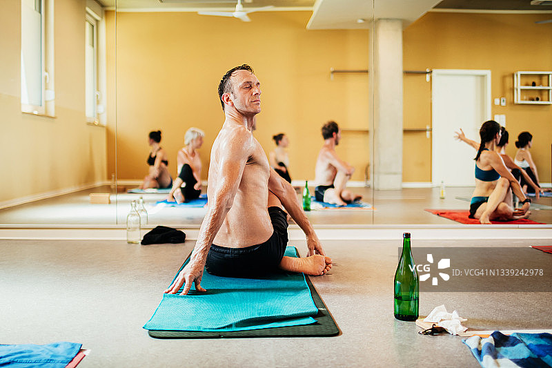 一名男子坐在毛巾上做瑜伽图片素材