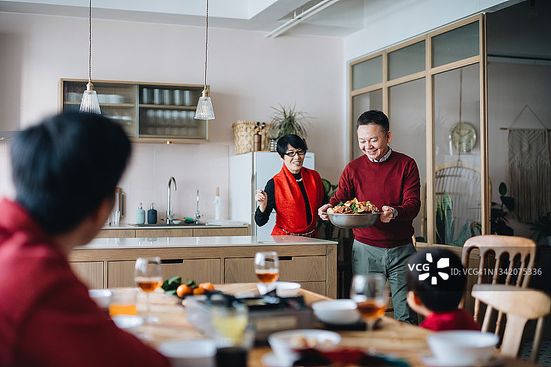 欢乐的亚洲家庭三代一起庆祝中国新年，爷爷奶奶在团圆饭上吃传统的中国盆菜图片素材