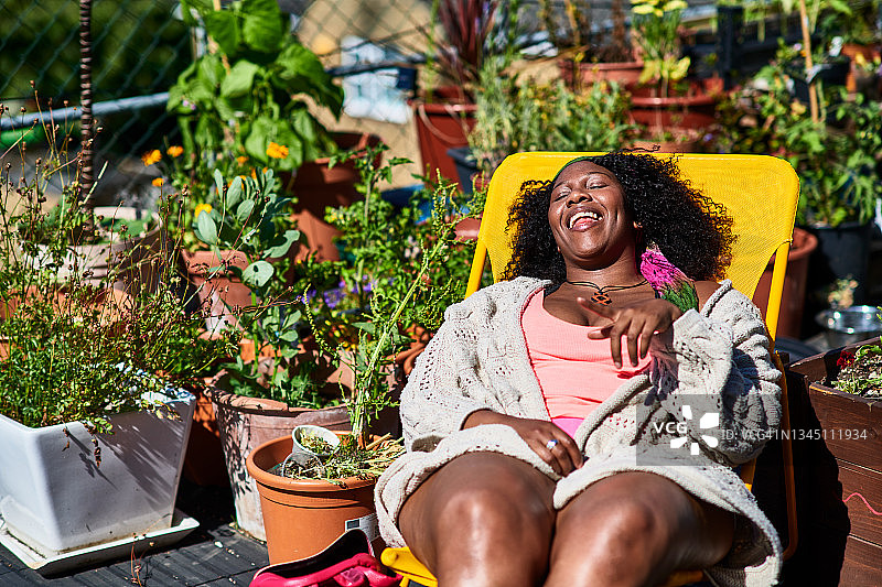 开朗的女人在屋顶露台的躺椅上休息图片素材