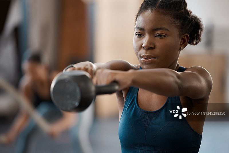 剪裁的照片，一个迷人的和运动的年轻女子与一个水壶铃在健身房图片素材