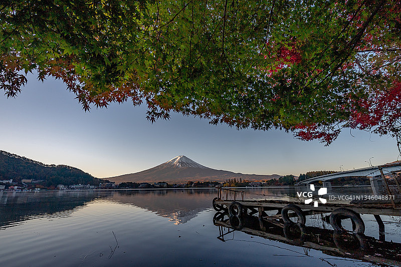 富士山倒影在水与生机勃勃的秋天树叶颜色前景在湖川口，日本秋天季节。图片素材