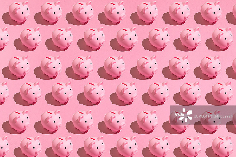粉红色的图案的小猪储蓄罐与黑色的眼睛在粉红色的背景。存钱的观念，省钱的观念。图片素材