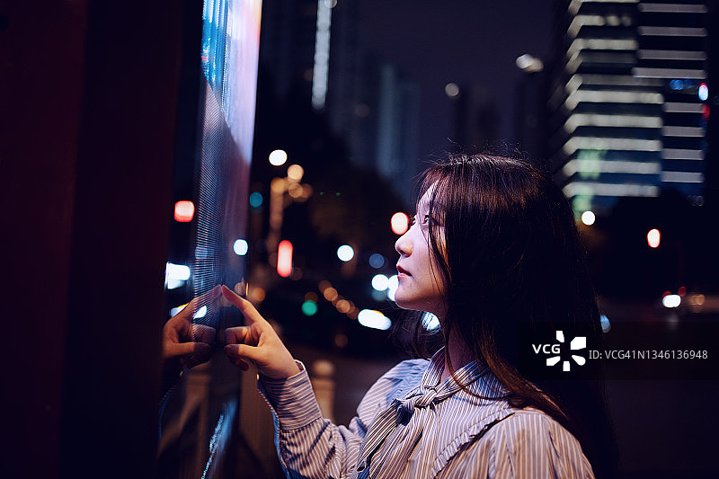 中国上海，一名年轻女子在街上使用触摸屏图片素材