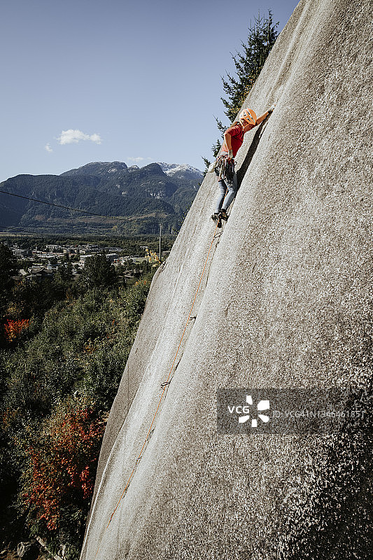 女攀岩者在阳光明媚的一天，攀登陡峭的岩石表面，公元前斯夸米什图片素材