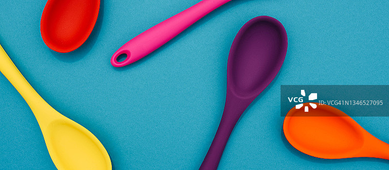 色彩鲜艳的勺子放在彩色背景上。图片素材