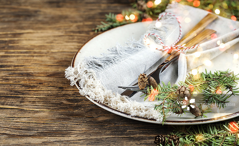 圣诞餐桌上有盘子、叉子、刀和带松果的冷杉树枝，图片素材