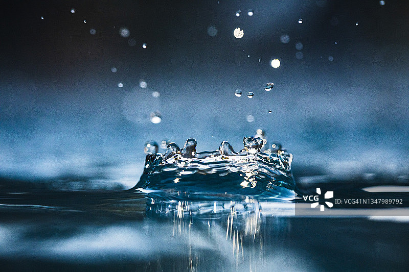 这是水滴落在深蓝色水面上的完美特写图片素材