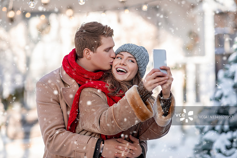 喜气洋洋的情侣一起享受初雪，一起自拍图片素材
