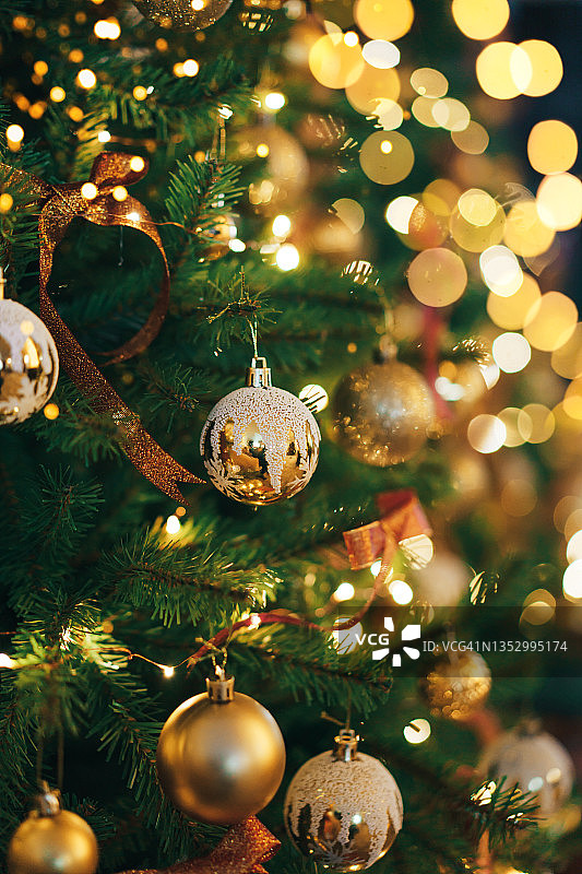 在闪闪发光的背景上有金色小玩意和花环的人造圣诞树树枝图片素材